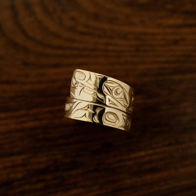 Hand carved 14k gold wrap ring carved by haida artist james sawyer featuring a formline wolf on a wooden background