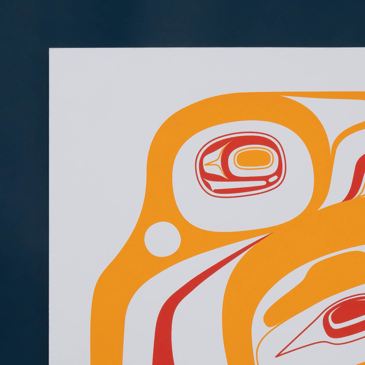A close-up of a stylized serigraph print featuring abstract shapes in orange, andred, on white paper, with a dark navy background around the print.