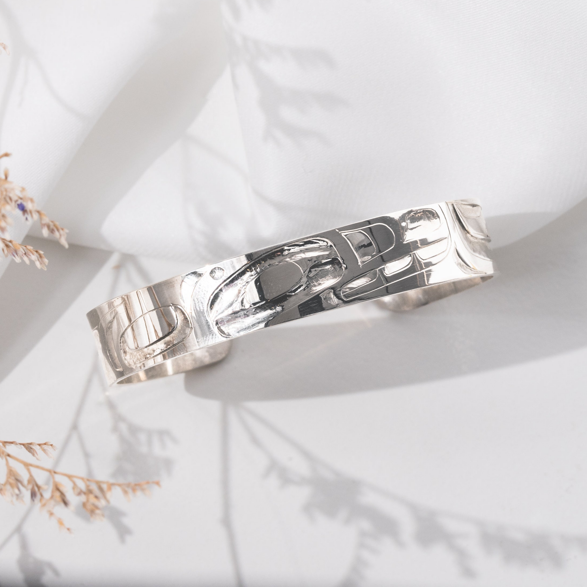 Sterling Silver haida formline orca bracelet hand carved by Haida jeweller Alvin Adkins on a light background