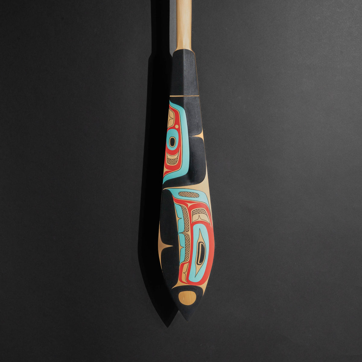 Decorative painted paddle with artistic design, showing the bottom of the paddle on a black background. 