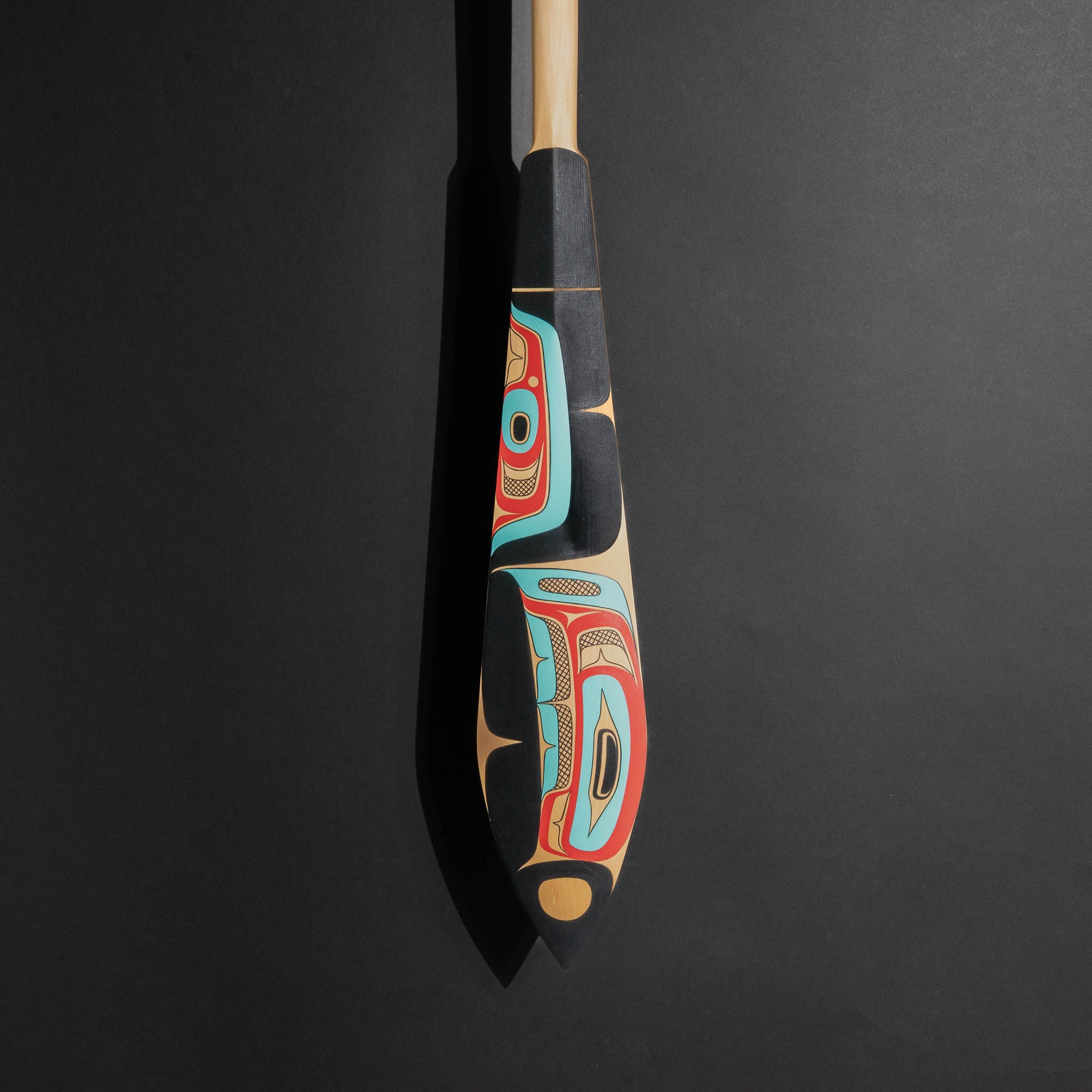 Decorative painted paddle with artistic design, showing the bottom of the paddle on a black background.