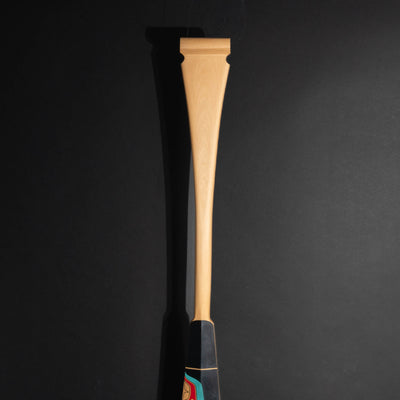 NEW: Closeup of the top part of a paddle made of yellow cedar with black, red, and blue paint on the bottom.