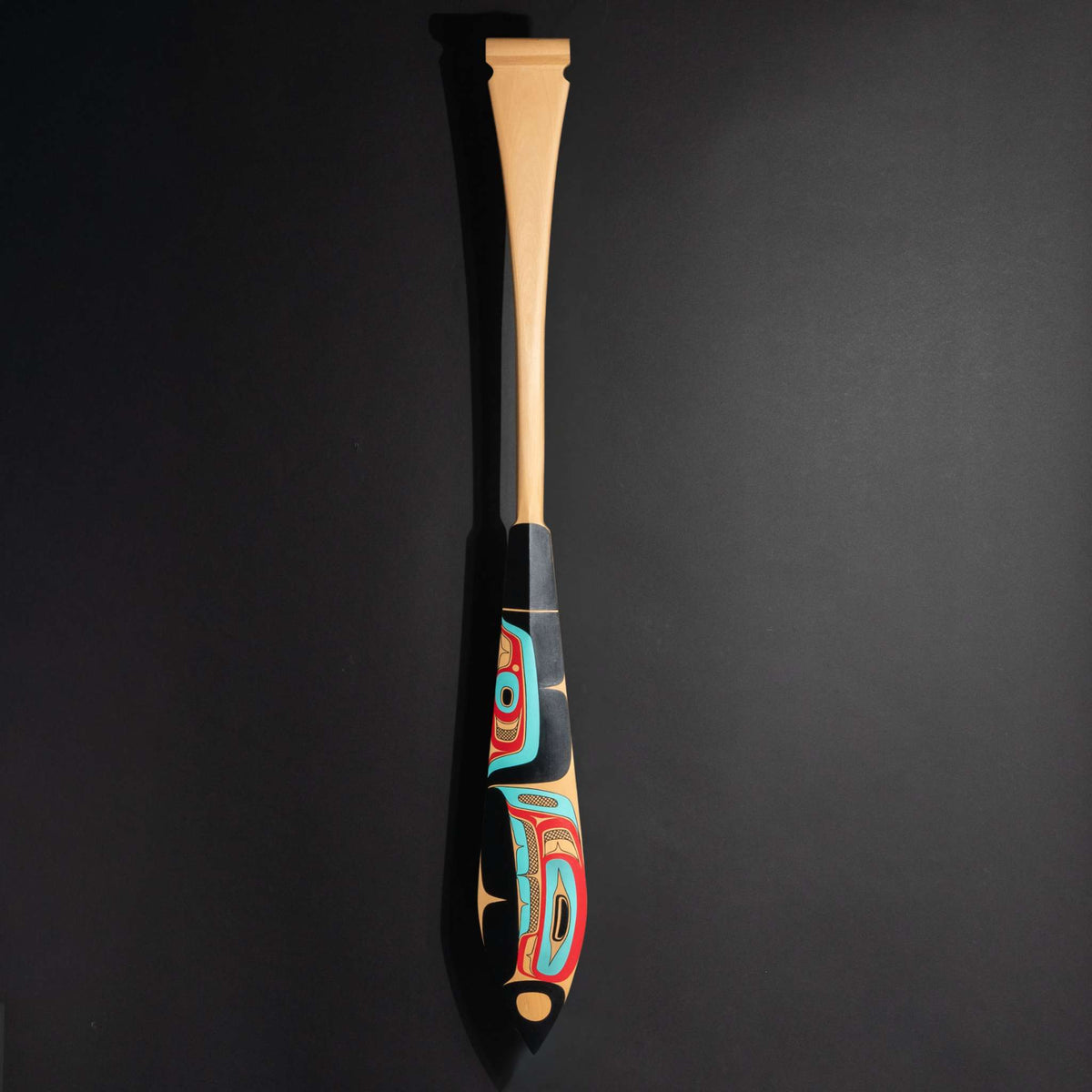 Haida formline paddle art by Alyson Bell showing the entire paddle on a black background. 