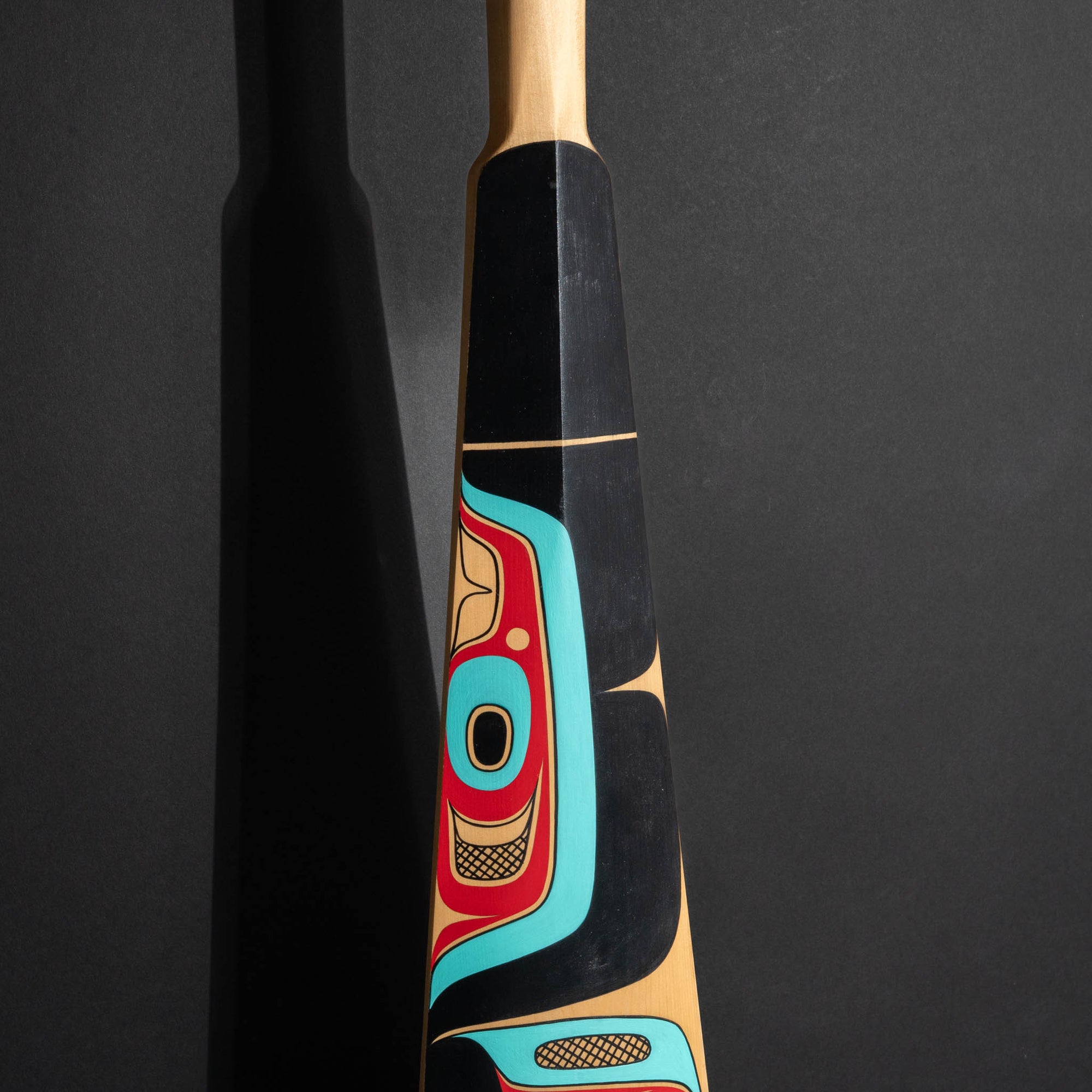 Closeup of the middle part of a paddle with abstract northwest coast formline shapes.