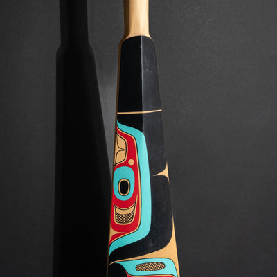 Closeup of the middle part of a paddle with abstract northwest coast formline shapes.