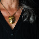 Gold pendant with chain worn by a woman with a black shirt