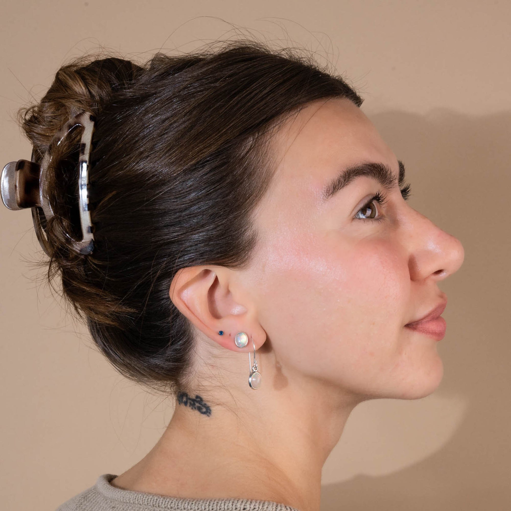 Model facing to the right with hair up and white opal studs and dangles.