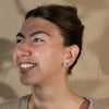 Model smiling and facing left with blue opal stud earrings and hair up.
