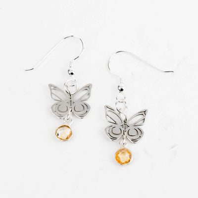 Butterfly earrings with round faceted orange citrine gemstones on a white background.