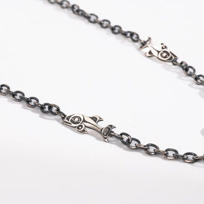 Close up of Salmon and chain links of Sterling Silver Killer whale and salmon necklace hand made by Ts'msyen artist Morgan Asoyuf on a white background