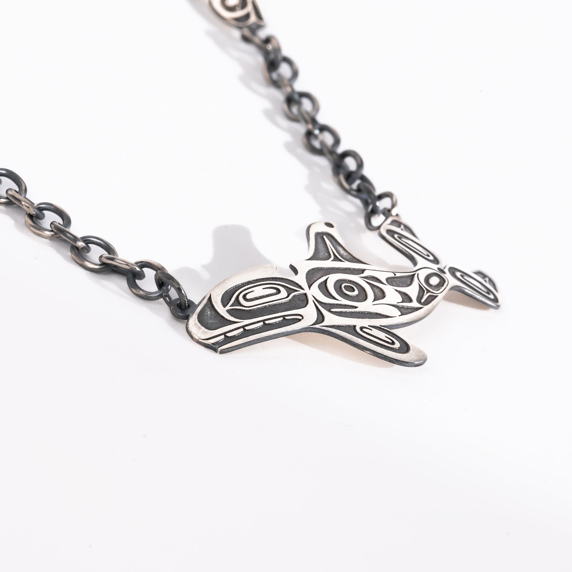 Close up of killer whale on Sterling Silver Killer whale and salmon necklace hand made by Ts'msyen artist Morgan Asoyuf on a white background