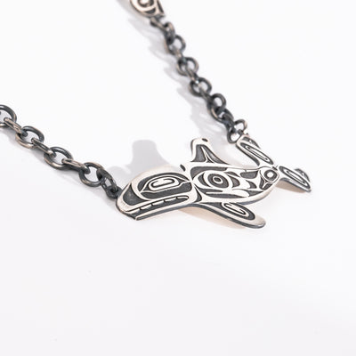Close up of killer whale on Sterling Silver Killer whale and salmon necklace hand made by Ts'msyen artist Morgan Asoyuf on a white background