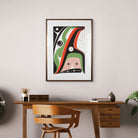 A black, green, and red framed artwork by Haida artist Robert Davidson above a dark brown desk and chair.