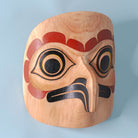 Saw-Whet Owl light wood Haida Mask by Alyson Bell on a blue background.
