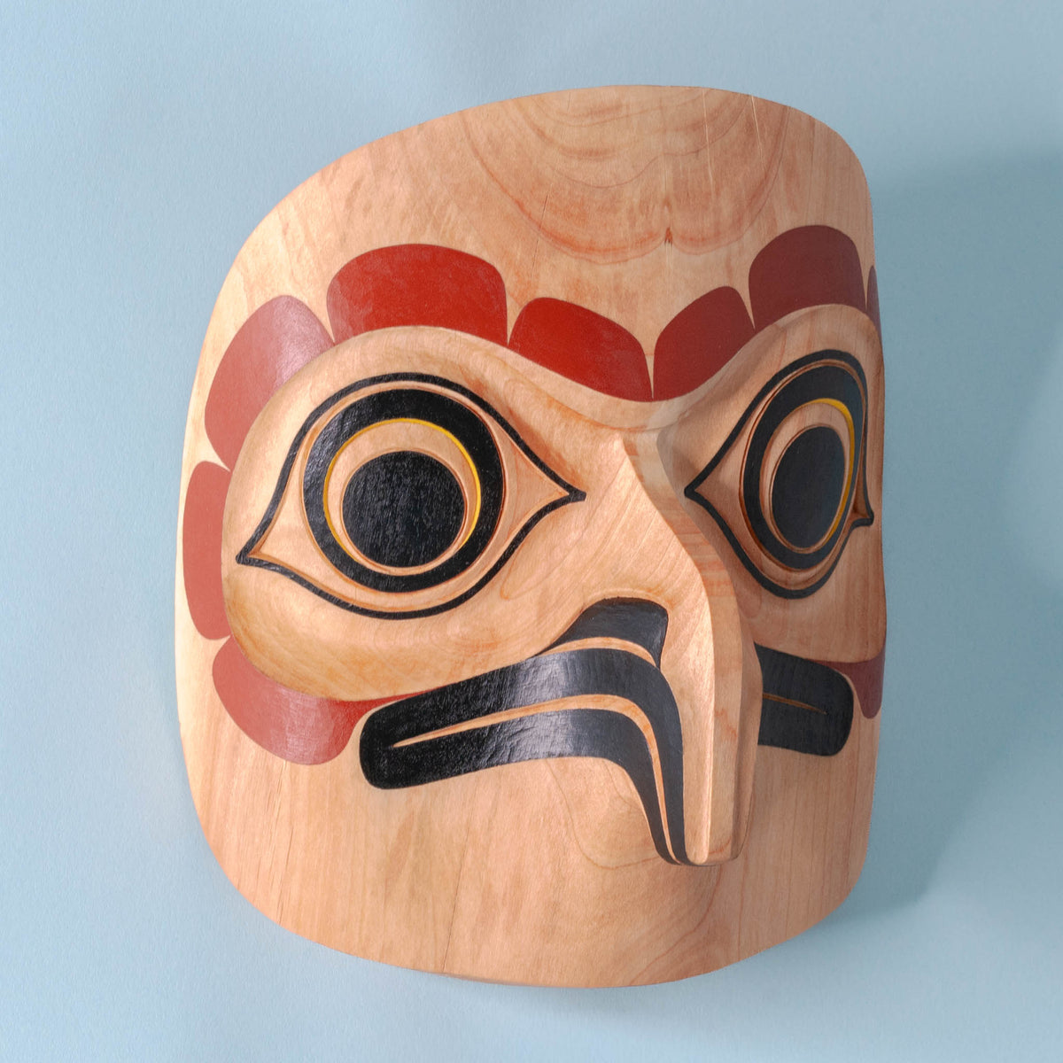 Saw-Whet Owl light wood Haida Mask by Alyson Bell on a blue background.