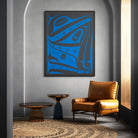 Modern interior with a blue abstract painting, brown leather chair, and round wooden table.