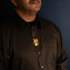 Gold pendant on a black chain worn by a man with a brown shirt