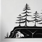 Close-up left corner of a black and white art print of a woman's face, arm, body, and trees growing overhead.
