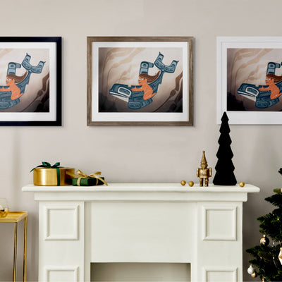 Framed fine art print a moment to vanish created by local haida artist Shoshannah Greene featuring a gilr riding a formline killer whale through a kelp bed on a wall above a white fireplace with decorative items.