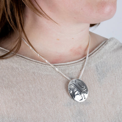 Haida Carver and Jeweller Alvin Adkins Sterling Silver Raven Pendant with 3mm curb chain on model side angle