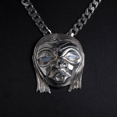Silver face necklace on a black background.