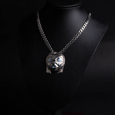 Silver face pendant with chain on a black mannequin against a black background