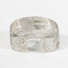 Backside of Sterling Silver Haida Raven bracelet with intricate formline designs showing the ravens wing hand carved by James Sayer Haida Jeweller on a white background