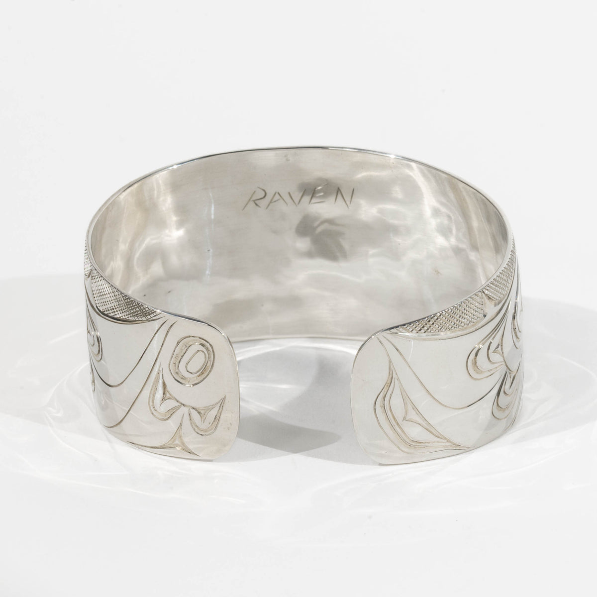 Backside of Sterling Silver Haida Raven bracelet with intricate formline designs showing the ravens wing hand carved by James Sayer Haida Jeweller on a white background
