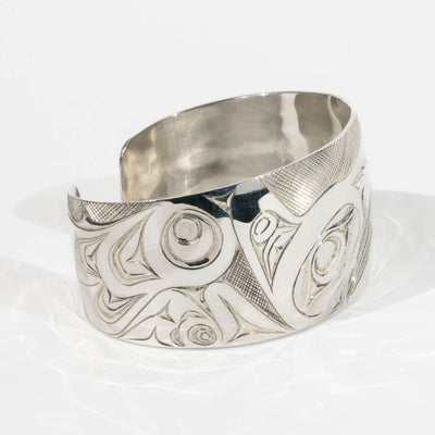 Left Side of Sterling Silver Haida Raven bracelet with intricate formline designs showing the ravens wing hand carved by James Sayer Haida Jeweller on a white background