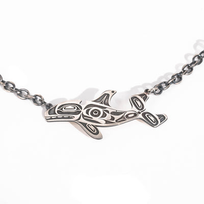 Close-up of blackened sterling silver killer whale and salmon necklace by Morgan Asoyuf.