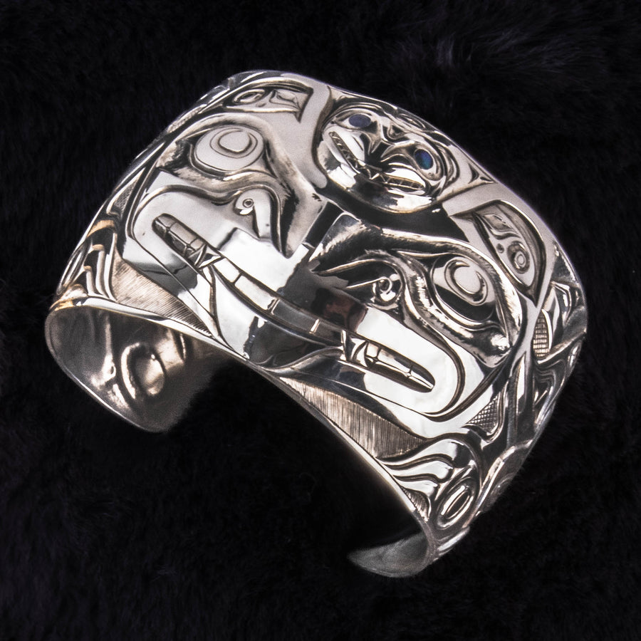 Silver bracelet with intricate designs on a dark background