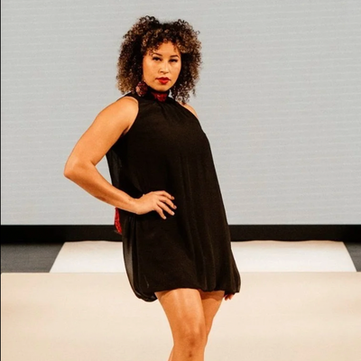 Woman wearing a black sleeveless dress against a neutral background