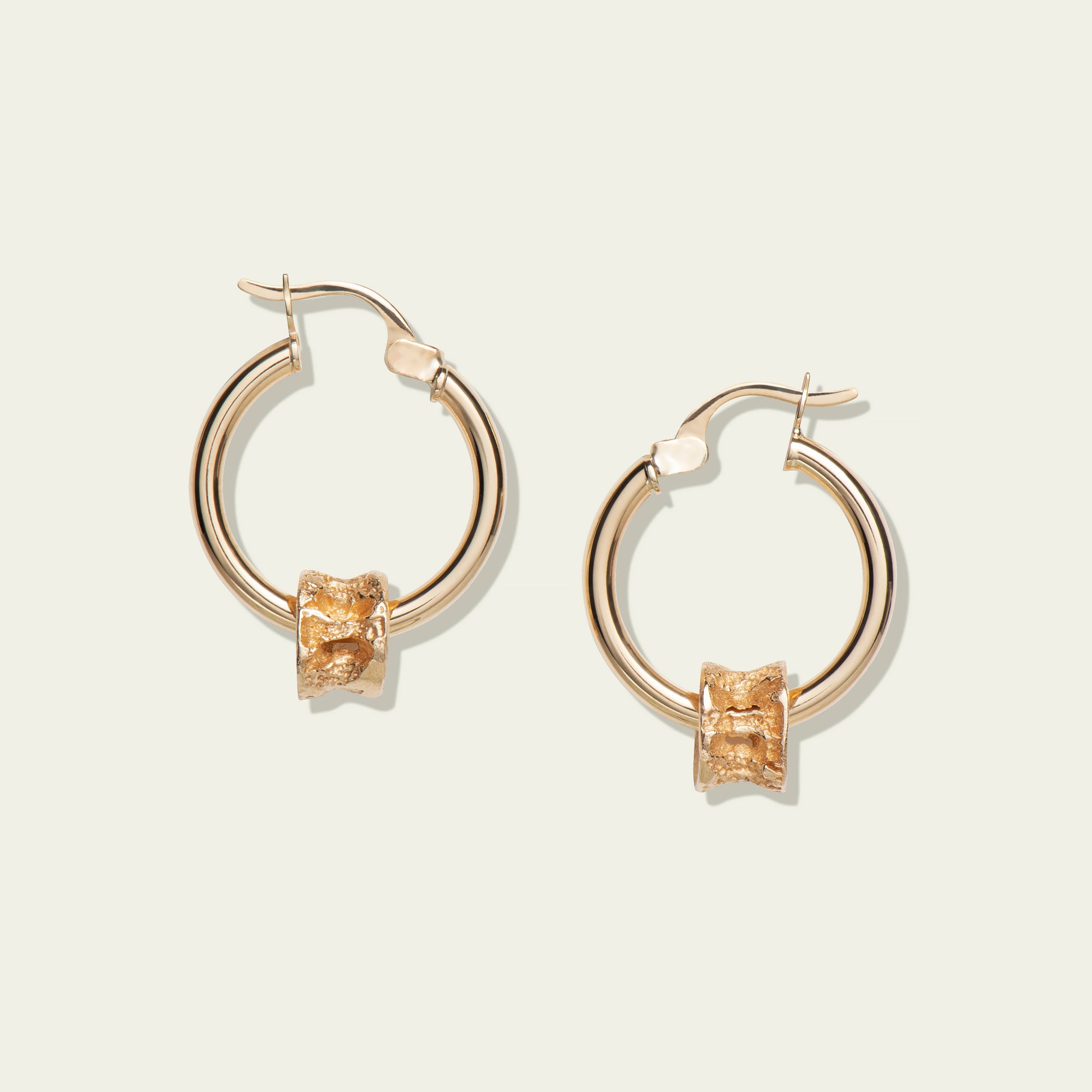 10K Gold Salmon Bone Vertebrae Ts'msyen Jewelry on Gold Hoops by Morgan Asoyuf on a white background.